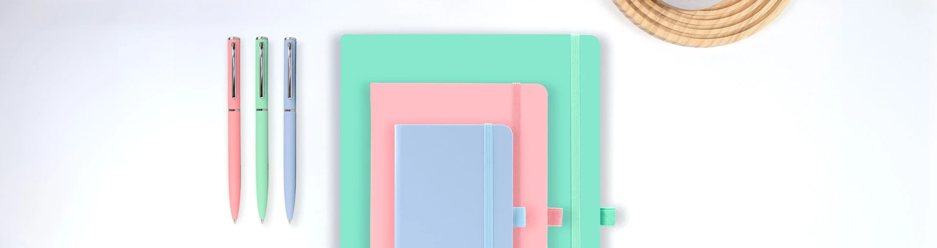 Wilson A4, A5 and A6 pastel notebooks stacked on top of each other with matching Wright pens next to them